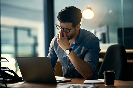 Shot of a young businessman experiencing stress during a late night at work